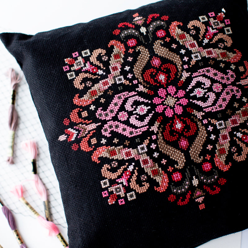 Folk mandala cross stitch kit design displayed on decorative pillow