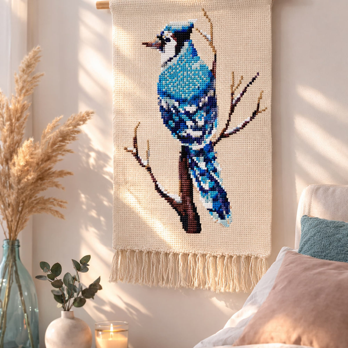 Blue Jay Cross Stitch Pattern PDF displayed as wall hanging decor, blue bird embroidery design, modern bird counted cross stitch pattern for home decor.