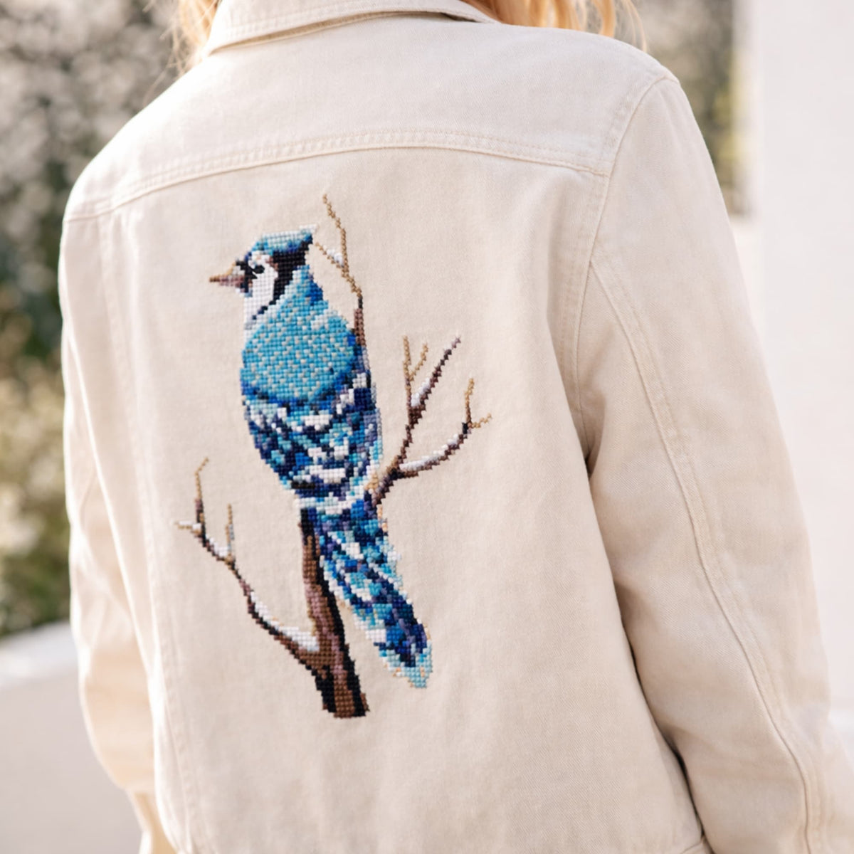 Blue Jay Cross Stitch Pattern PDF displayed on denim jacket back, blue bird embroidery design, modern bird counted cross stitch pattern.
