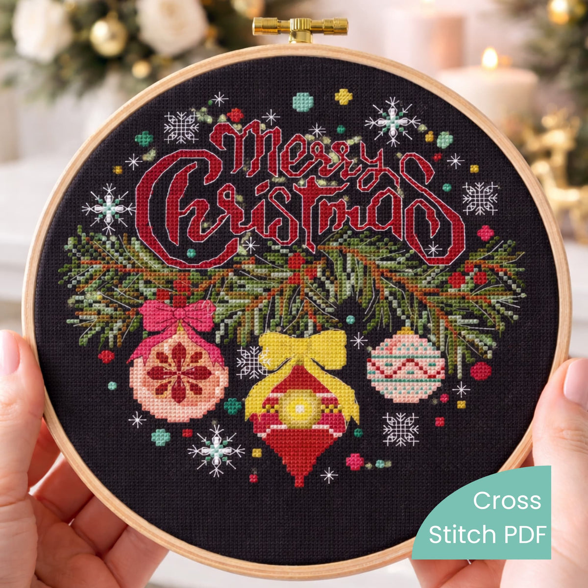 Close-up of Merry Christmas cross stitch hoop on black fabric with red lettering and holiday ornaments