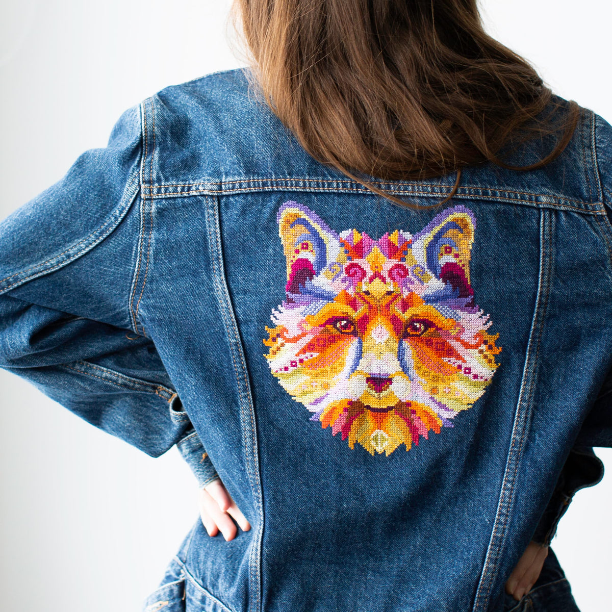 Colorful swirl fox counted cross stitch kit displayed on denim jacket back with vibrant folk animal embroidery design.