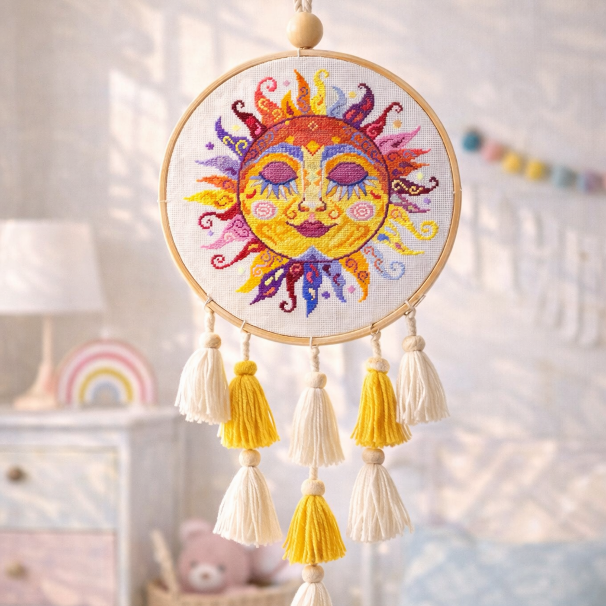Colorful swirl sun cross stitch pattern displayed in embroidery hoop with tassels, handmade folk sun embroidery wall decoration, child room decor.