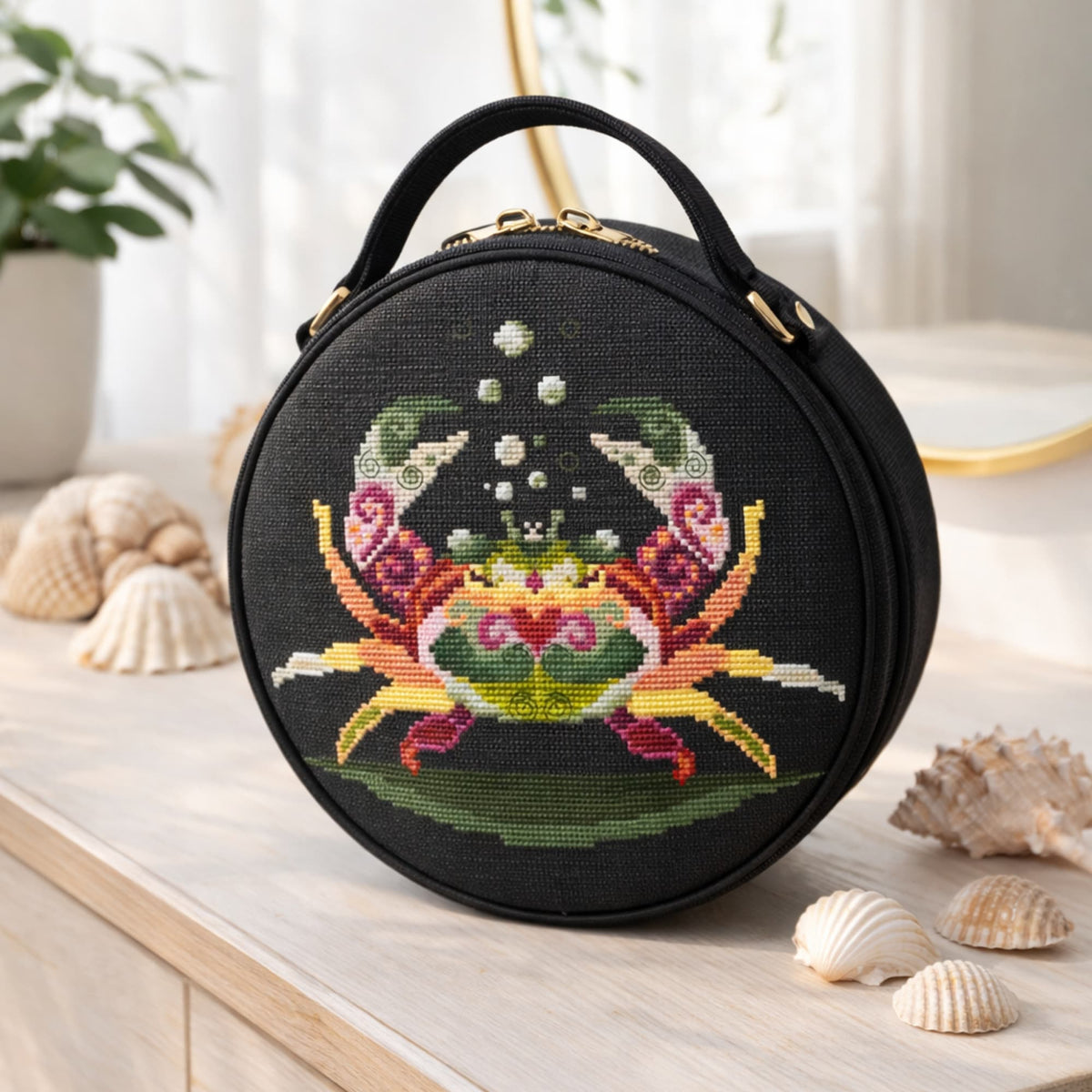 Crab cross stitch kit design shown on round black handbag, colorful ocean crab embroidery project