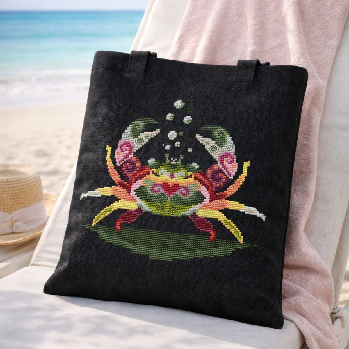 Crab cross stitch kit displayed on black tote bag at the beach, ocean themed DIY embroidery project