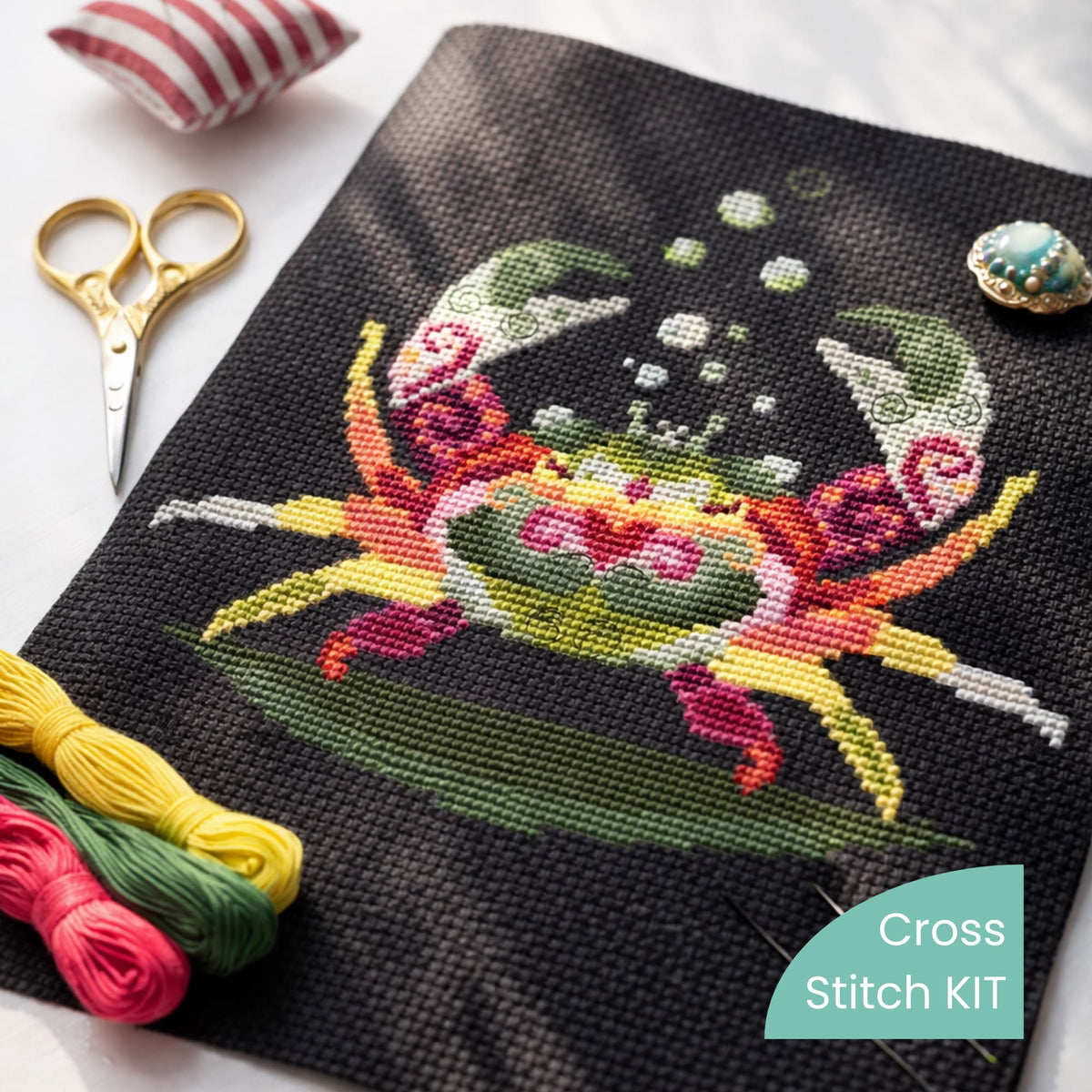 Crab cross stitch kit flat lay with embroidery floss, scissors and needle, DIY ocean crab embroidery set on black Aida fabric