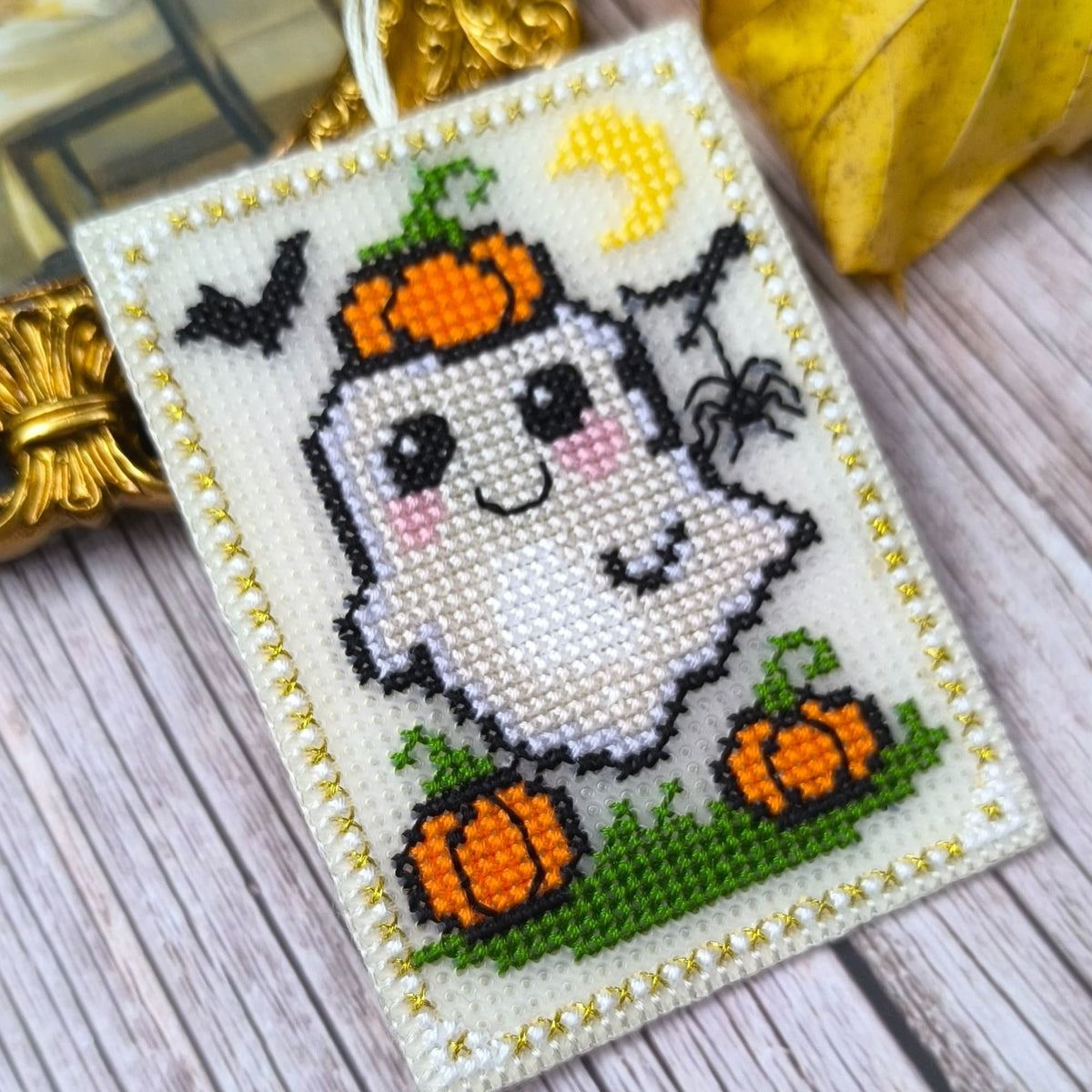 Cross-stitched ghost with pumpkins and spider on a white background