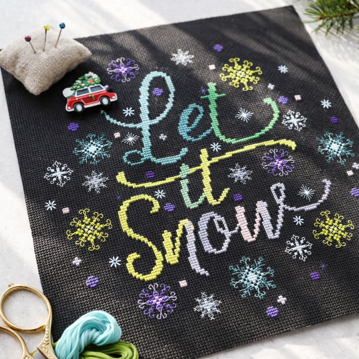 Cross Stitch Pattern Let It Snow PDF – Winter Snowflake Typography Cross Stitch Pattern stitched on black fabric with colorful threads