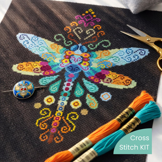 Dragonfly cross stitch kit flat lay with embroidery threads, needle and scissors on black fabric