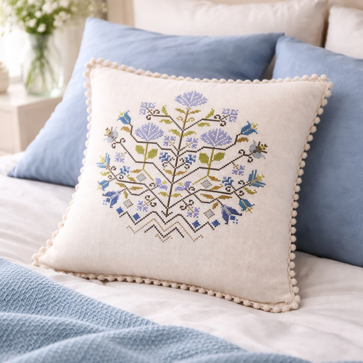 Finished cross stitch pillow featuring Blue Flowers Sampler design. Example of completed embroidery made using the cross stitch pattern PDF. Decorative floral folk inspired counted cross stitch.