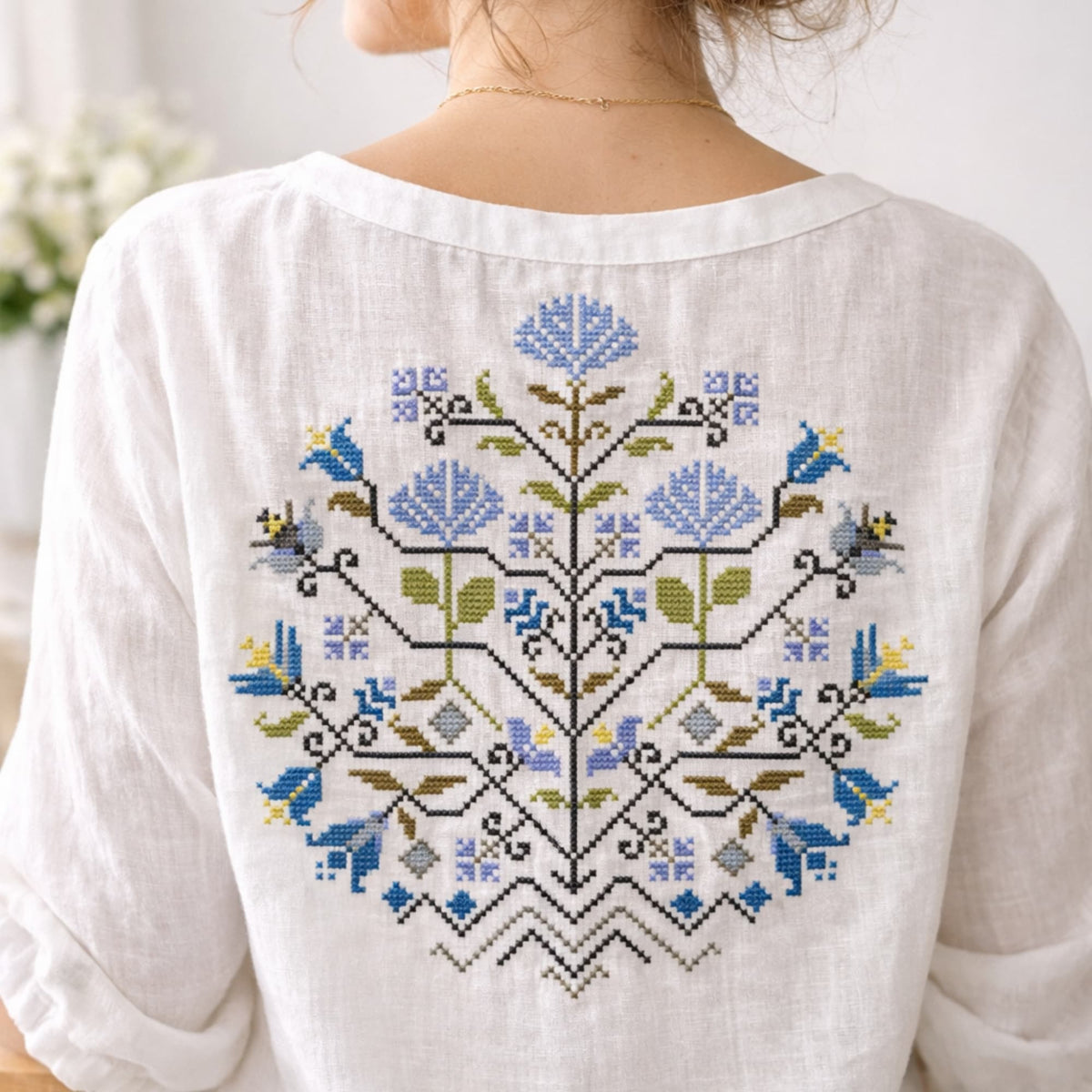 Finished embroidered blouse back featuring Blue Flowers Sampler folk floral motif. Example of completed embroidery stitched using the complete cross stitch kit. Wearable counted cross stitch embroidery design.
