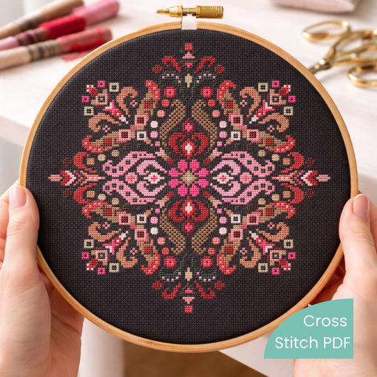 Folk mandala counted cross stitch pattern PDF displayed in embroidery hoop on black fabric held in hands