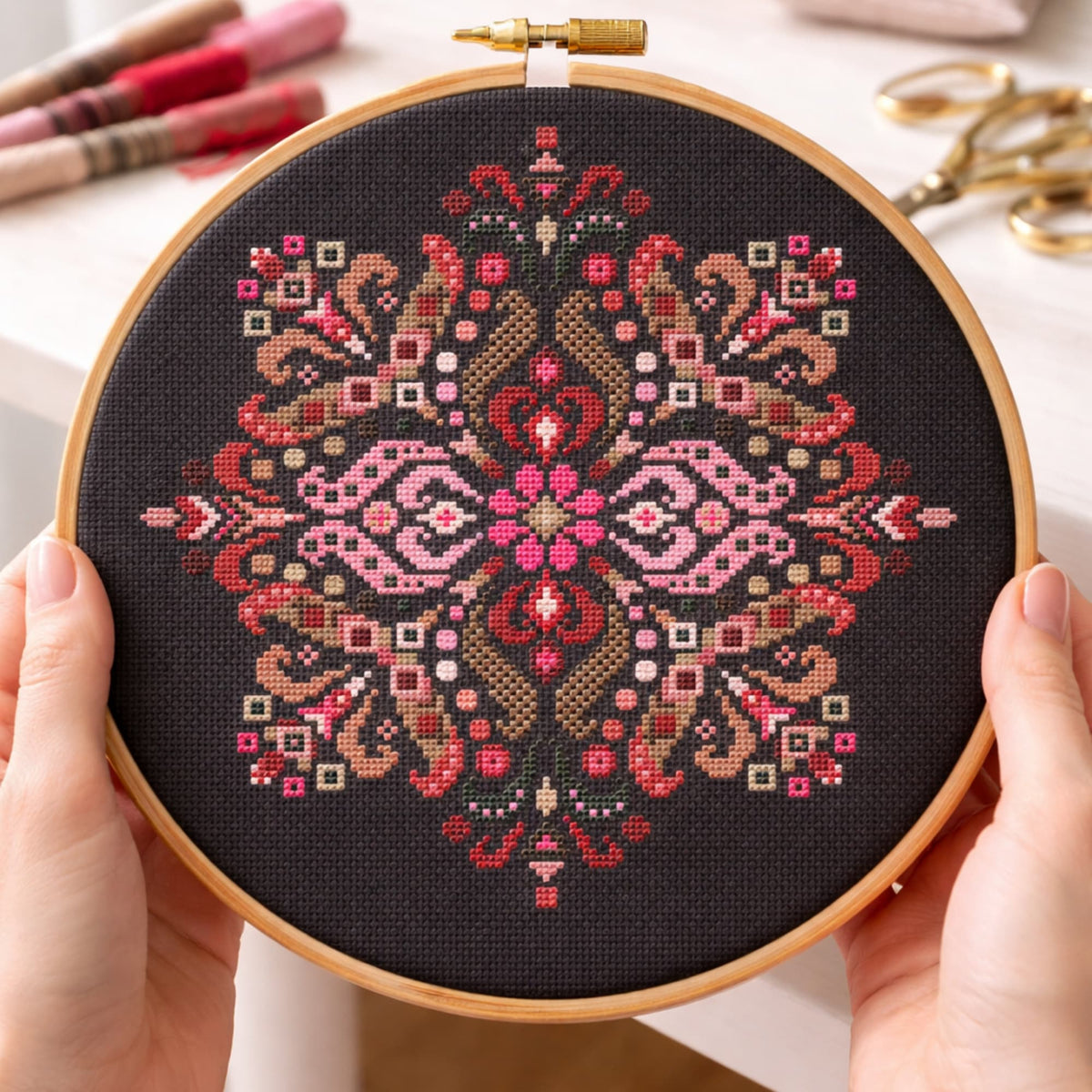 Folk mandala cross stitch kit design shown in embroidery hoop on black fabric, traditional embroidery DIY project