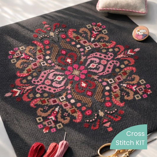 Folk mandala cross stitch kit flat lay with embroidery threads, needle and scissors on black fabric