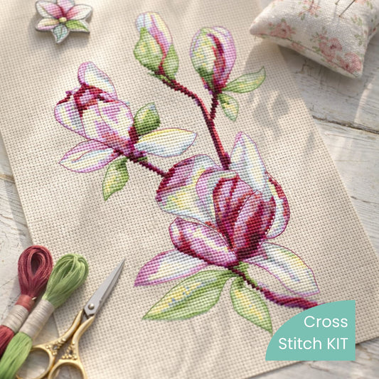 Magnolia cross stitch kit materials and finished magnolia embroidery on linen fabric, threads and tools included in kit.