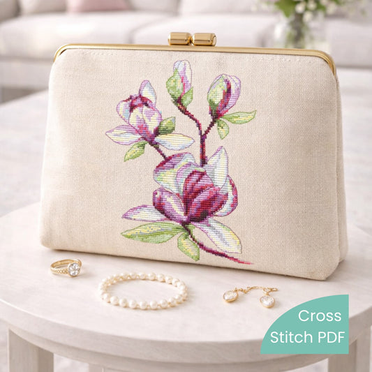 Magnolia cross stitch pattern stitched on elegant linen clutch, pink floral embroidery example, finished piece shown for display only.