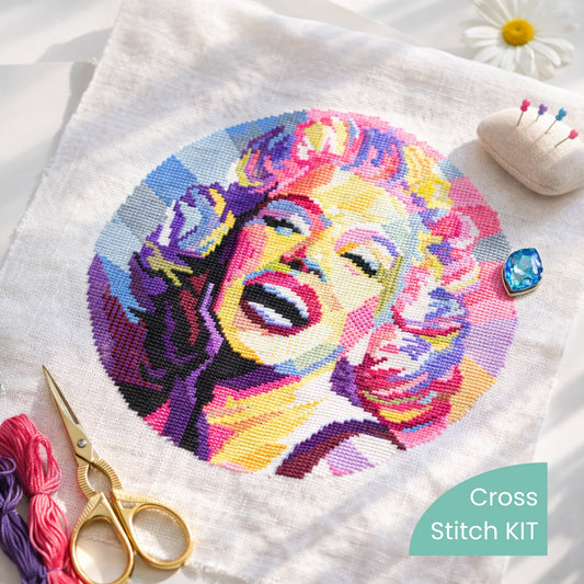 Marilyn Monroe Counted Cross Stitch Kit showing finished portrait embroidery with threads, scissors and accessories.