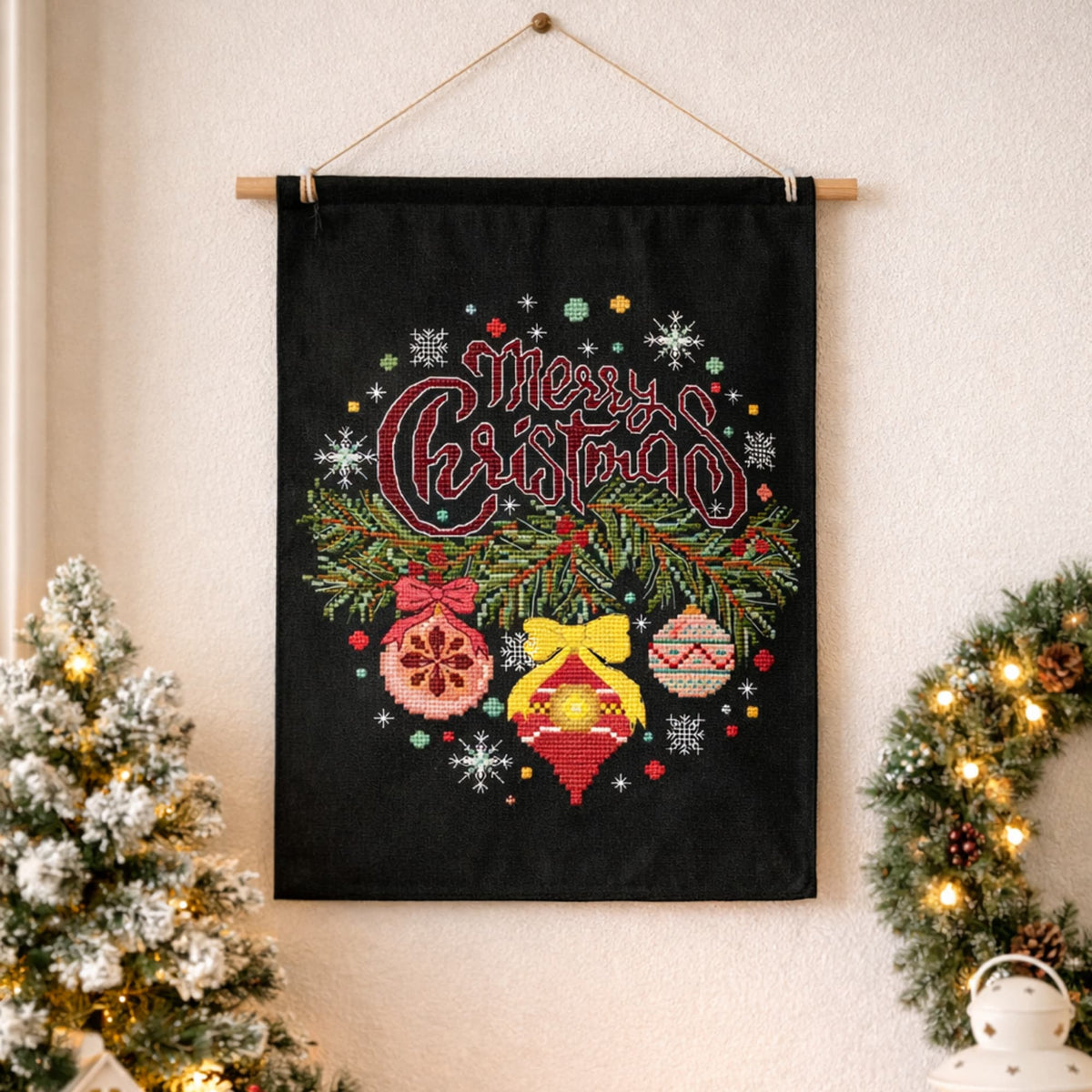 Merry Christmas counted cross stitch design displayed as wall hanging with Christmas tree and wreath decorations
