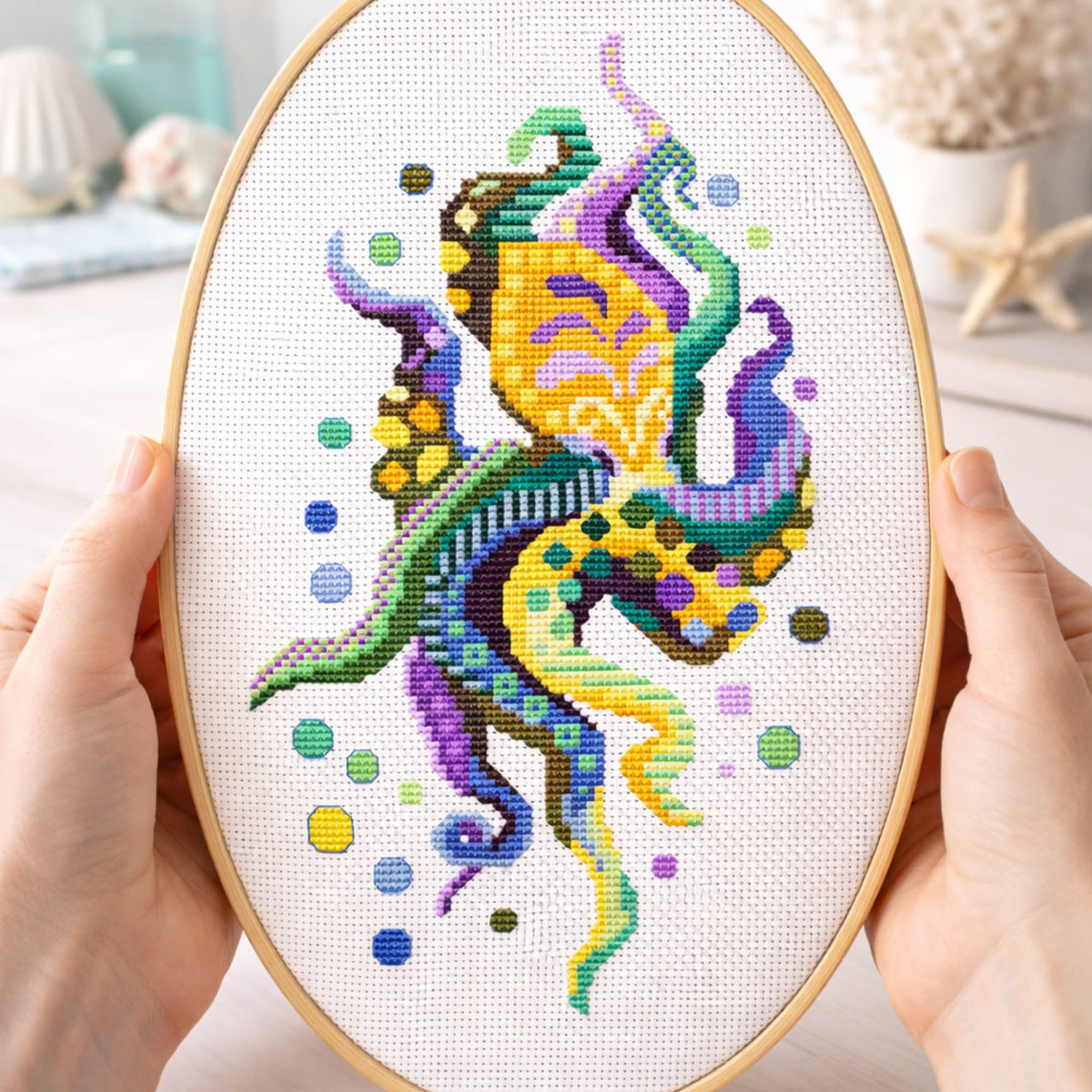 Modern octopus cross stitch pattern PDF displayed in embroidery hoop held in hands with detailed ocean design.