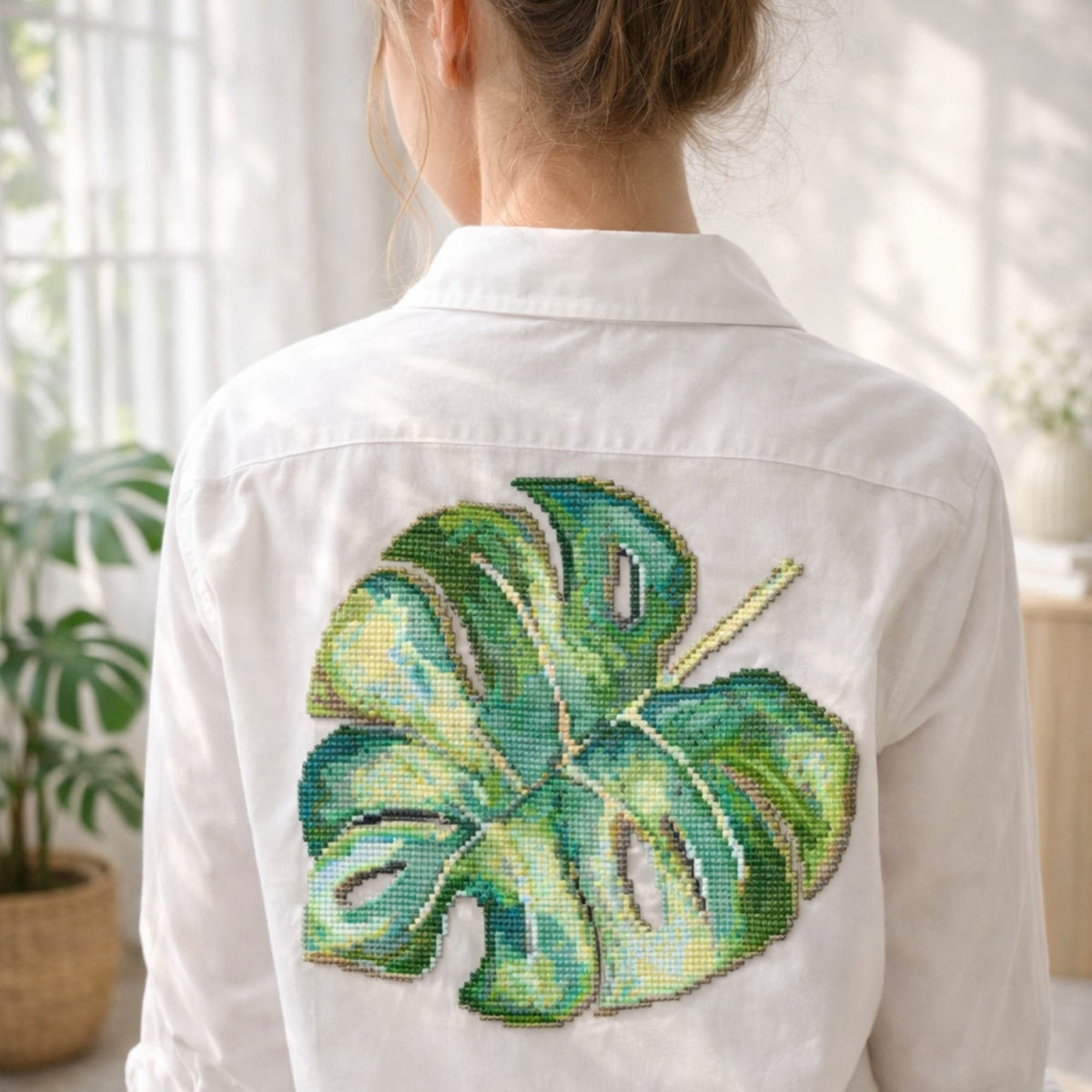 Monstera leaf cross stitch kit stitched on white shirt, modern botanical embroidery design for clothing.