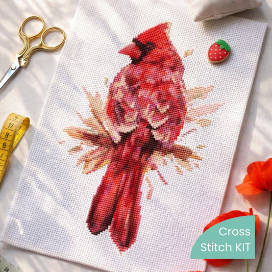 Northern Cardinal counted cross stitch kit materials displayed with stitched fabric and tools, premium bird embroidery kit for creating realistic cardinal needlework art.