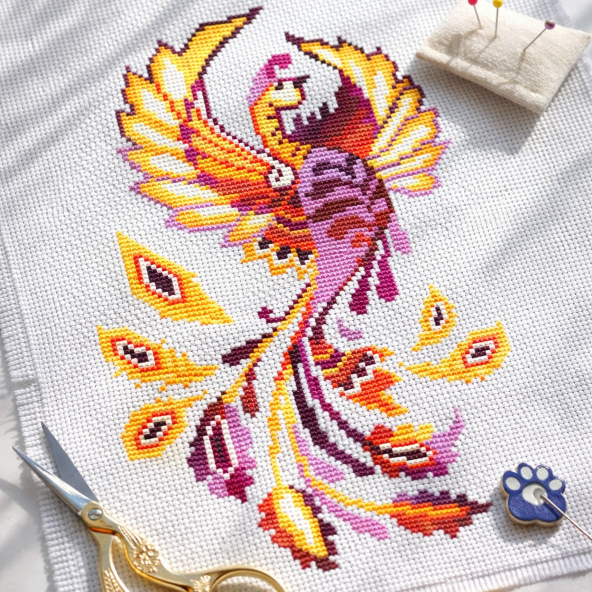 Phoenix Cross Stitch Kit – colorful firebird embroidery design with bright orange and magenta tones stitched on white fabric, premium artistic needlework kit for modern home decor