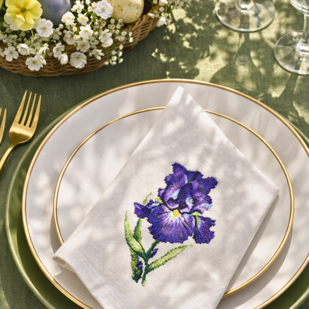 Purple blue iris embroidery stitched on natural fabric napkin displayed on an elegant spring table setting