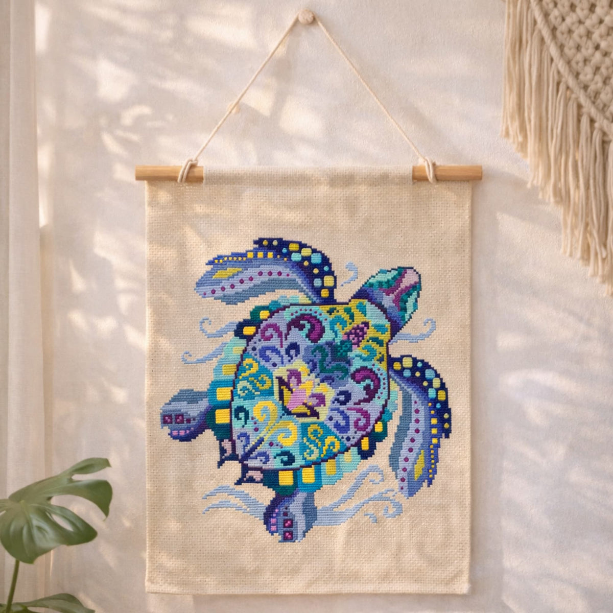 Sea turtle counted cross stitch kit displayed as wall hanging on natural fabric with coastal decor