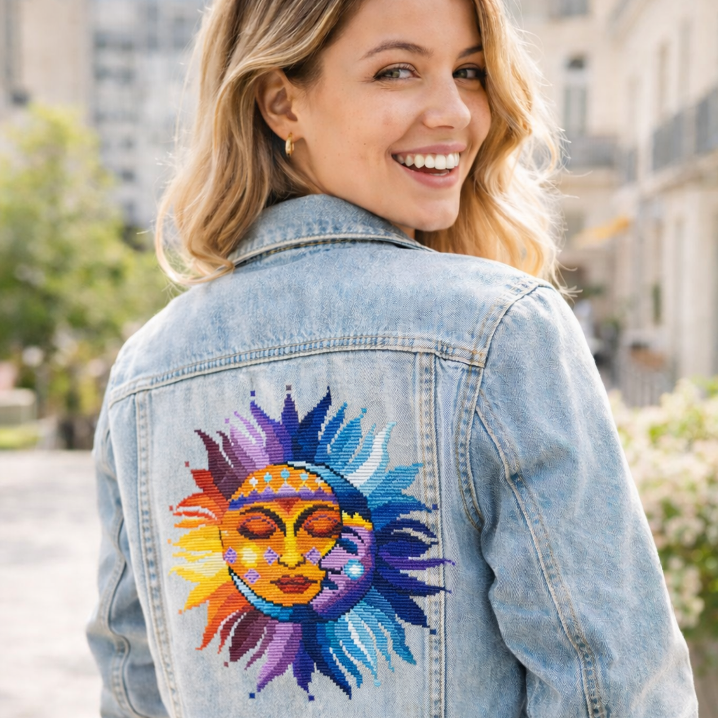 Sun and Moon cross stitch embroidery on denim jacket back, vibrant celestial sun and moon face design, modern wearable folk embroidery