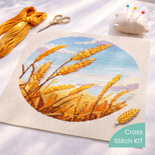 Wheat Field Counted Cross Stitch Kit with golden wheat landscape embroidery design stitched on fabric with embroidery threads, scissors and pin cushion.