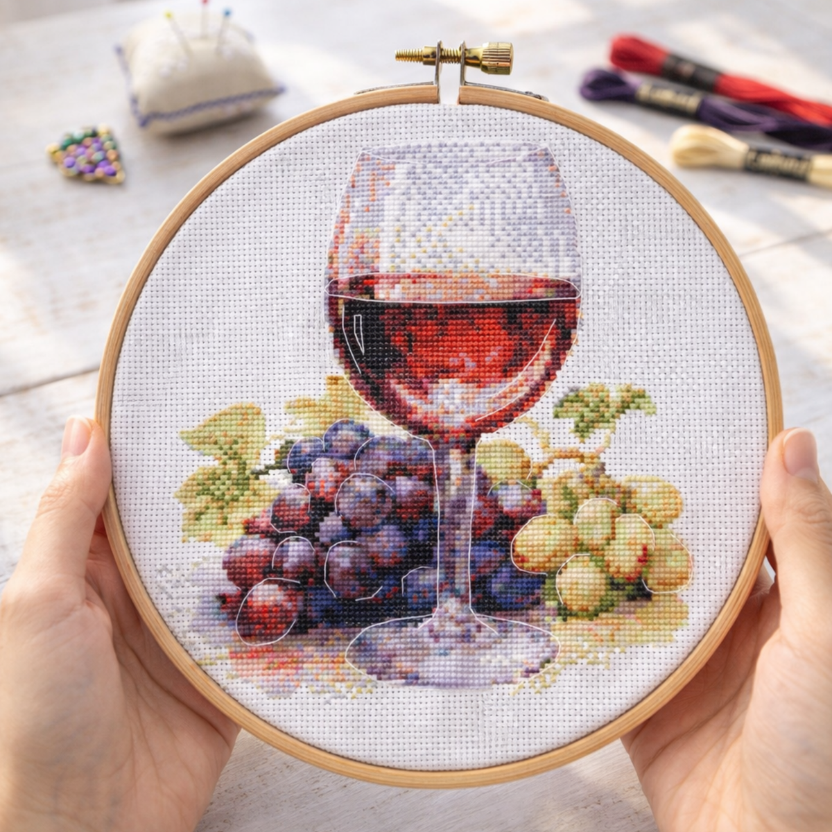 Wine glass and grapes cross stitch kit design shown in embroidery hoop, realistic wine still life DIY embroidery project