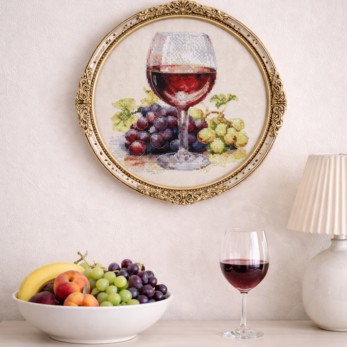 Wine glass and grapes cross stitch kit displayed in decorative frame as wall art, realistic still life embroidery project