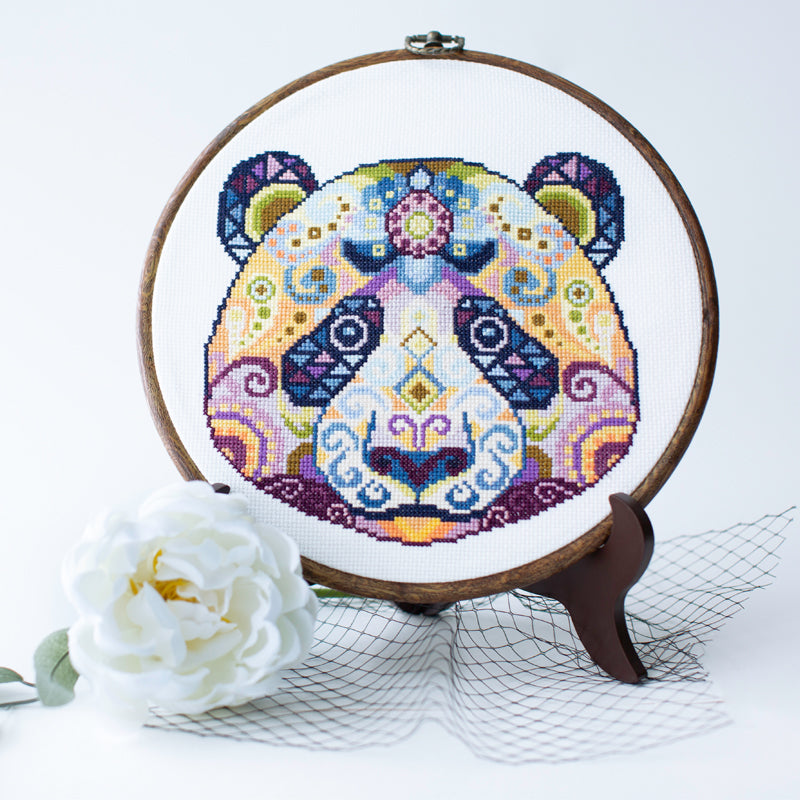 Folk modern panda counted cross stitch kit displayed in embroidery hoop and threads with detailed colorful panda design ready for stitching.